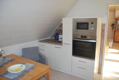 a small kitchen with a microwave and a table at NEU! Schönes Urlaubsdomizil an der Nordsee in Stedesdorf