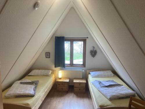 um quarto no sótão com 2 camas e uma janela em Ferienhaus Spitzbergen Nr. 105 em Bad Arolsen