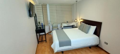 a bedroom with a large white bed and a desk at Hotel Montecarlo in Ibarra