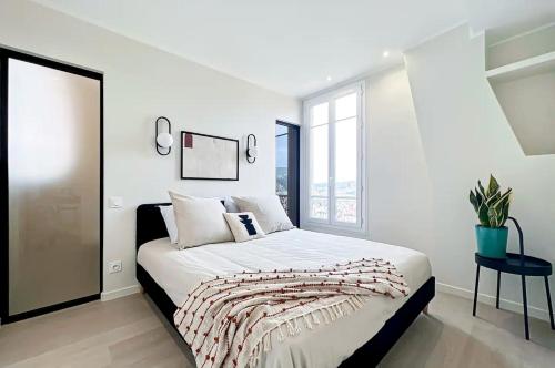 a white bedroom with a bed and a window at LE PANORAMIQUE in Nice