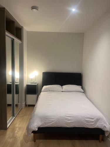 a bedroom with a large bed with white sheets at AEROPARTMENT & AEROTEL, London Heathrow Airport, Terminal 4, EV Stations & Cheap Parking on site! in West Bedfont