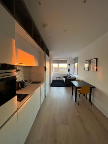 a kitchen and a living room with a table at AEROPARTMENT & AEROTEL, London Heathrow Airport, Terminal 4, EV Stations & Cheap Parking on site! in West Bedfont