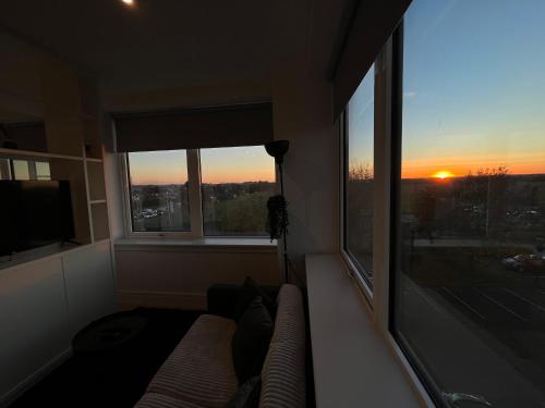 a living room with a couch and a large window at AEROPARTMENT & AEROTEL, London Heathrow Airport, Terminal 4, EV Stations & Cheap Parking on site! in West Bedfont