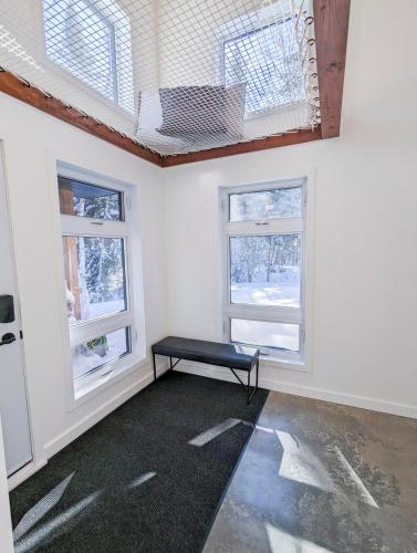 a room with two windows and a bench in it at CHALET MISTA - Charlevoix - Repère de ski moderne en nature in Saint-Tite-des-Caps