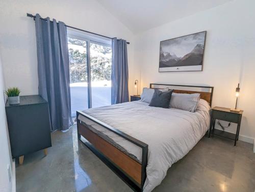 a bedroom with a bed and a large window at CHALET MISTA - Charlevoix - Repère de ski moderne en nature in Saint-Tite-des-Caps