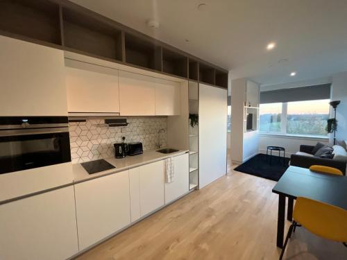 a kitchen with white cabinets and a living room at AEROPARTMENT & AEROTEL, London Heathrow Airport, Terminal 4, EV Stations & Cheap Parking on site! in West Bedfont