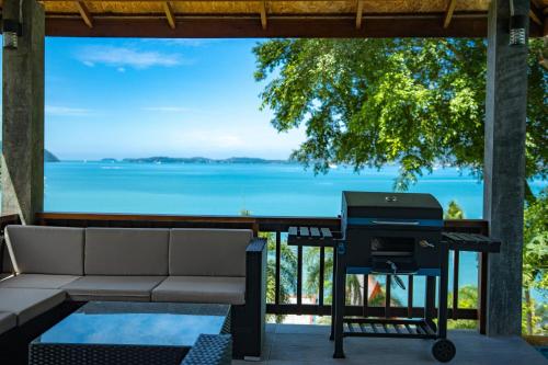 a barbecue grill on a patio with a view of the ocean at 悬崖别墅 无边海景 直达海滩 五卧泰式独栋私人泳池别墅 超漂亮日出 in Phuket Town