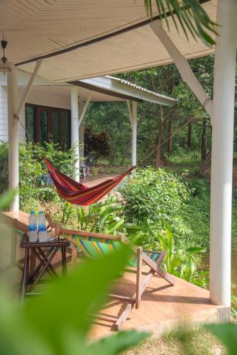 a hammock on the porch of a house at The River Retreat Koh Mak in Ko Mak