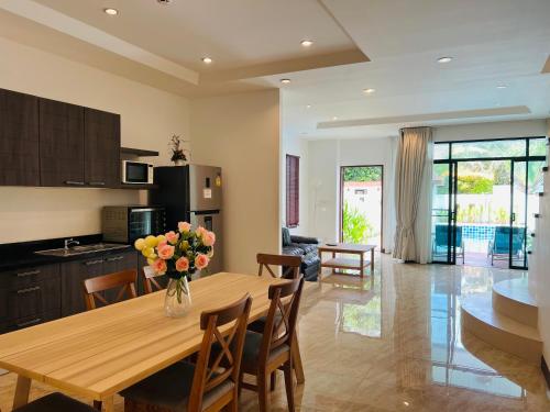 a kitchen and dining room with a table and flowers at Kamala Beach 3-bedroom villa near Fantasea with high-speed Wi-Fi and private pool in Kamala Beach