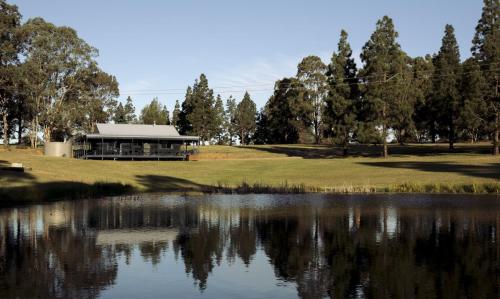 a building next to a lake with trees at Palmers Lane Estate Hunter Valley in Pokolbin