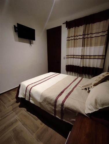 1 dormitorio con 1 cama y TV en la pared en Casa Mictlan. Habitaciones en el Centro de Mitla., en San Pablo Villa de Mitla