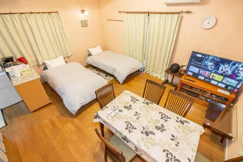 a living room with a television and a table and chairs at おもちゃ王国と北軽井沢の大自然を満喫できる貸別荘 in Karuizawa