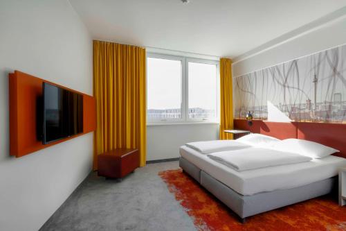um quarto com uma cama e uma grande janela em Campanile Berlin Brandenburg Airport em Schönefeld