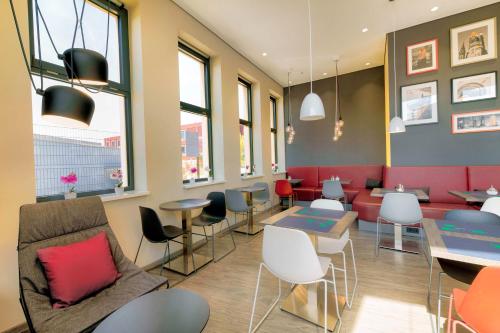 a restaurant with tables and chairs and windows at Campanile Berlin Brandenburg Airport in Schönefeld
