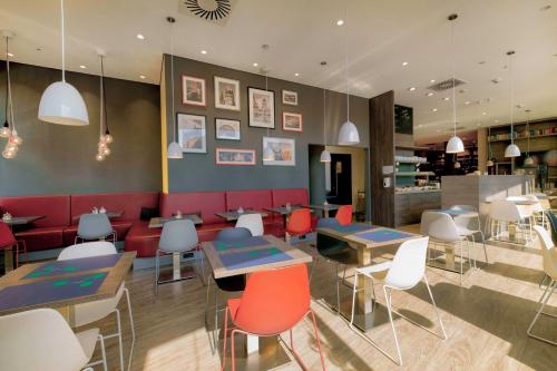 a restaurant with tables and chairs and a counter at Campanile Berlin Brandenburg Airport in Schönefeld