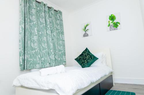 Cama en habitación con cortina verde y blanca en 4 bedroom Bungalow, en Slades Green