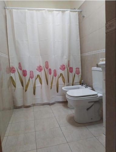 La salle de bains est pourvue de toilettes et d'un rideau de douche avec des fleurs roses. dans l'établissement GyS, à Santa Rosa