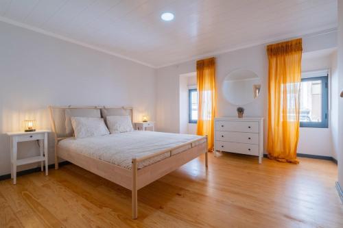 a white bedroom with a bed and two windows at Casa da Antonieta in Ponta Delgada