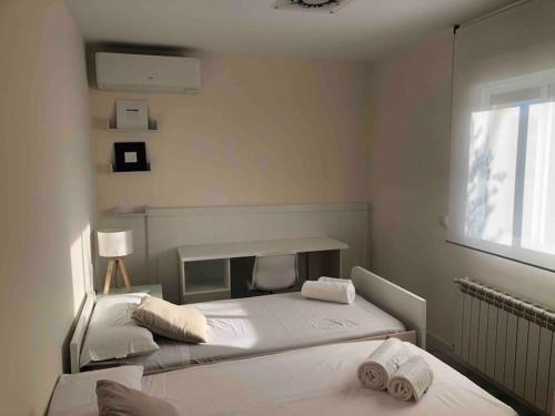 ein weißes Schlafzimmer mit 2 Betten und einem Fenster in der Unterkunft El Encinar de Carol in Mesones