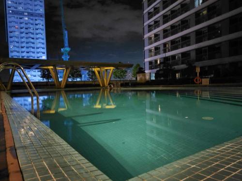 HOMESNAP CONDOTEL FAME RESIDENCE MANDALUYONG في مانيلا: مسبح فارغ بالليل بالمباني