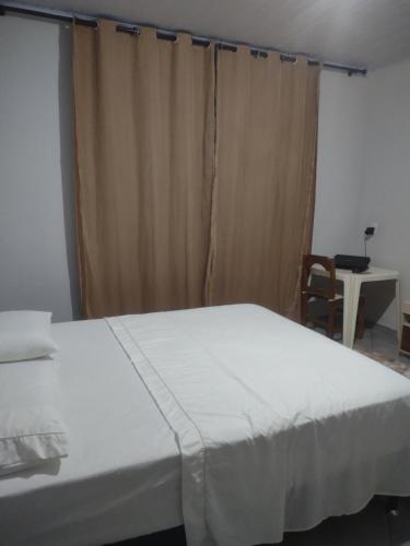 a bed in a room with a curtain and a chair at Casa Fortes in Várzea Grande