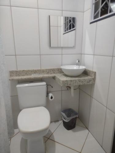 a bathroom with a white toilet and a sink at Casa Fortes in Várzea Grande