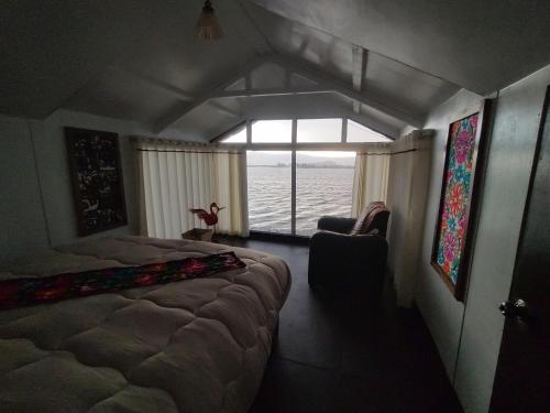 a bedroom with a bed and a chair and a window at TITICACA WORLDWIDE LODGE in Puno