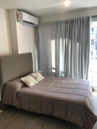 a bed in a bedroom with a large window at Cálido Apart en el corazón de Buenos Aires con piscina in Buenos Aires