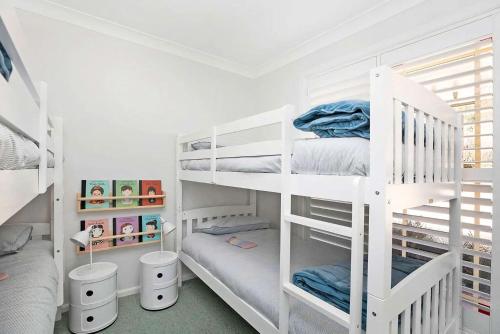 1 dormitorio con literas blancas y sábanas azules en Avonlea, Bowral, Southern Highlands, en Bowral