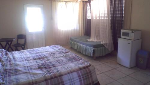 a bedroom with a bed and a chair and two windows at Maracas Bay View in Maracas Bay Village