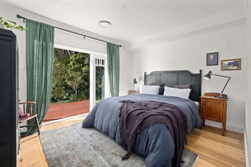 een slaapkamer met een bed en een groot raam bij Birdsong, Kangaroo Valley in Barrengarry