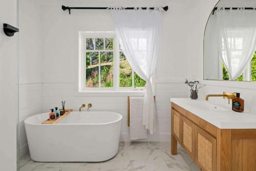 een badkamer met een bad, een wastafel en een raam bij Birdsong, Kangaroo Valley in Barrengarry