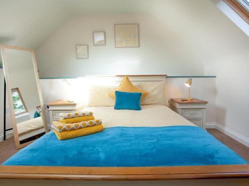 um quarto com uma cama grande e lençóis azuis em Uk45541-old Stable Cottage em Sticklepath