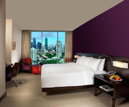ein Hotelzimmer mit einem großen Bett und einem großen Fenster in der Unterkunft Megapolis Hotel Panama in Panama-Stadt