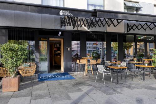 a restaurant with tables and chairs in front of a building at Hotel Indigo Antwerp City Centre by IHG in Antwerp