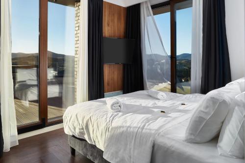 a bedroom with a white bed with a large window at 21st Century Zlatibor Residence, Spa & Wellness by Adora in Zlatibor