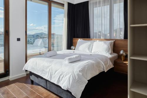 a bedroom with a large bed with a large window at 21st Century Zlatibor Residence, Spa & Wellness by Adora in Zlatibor