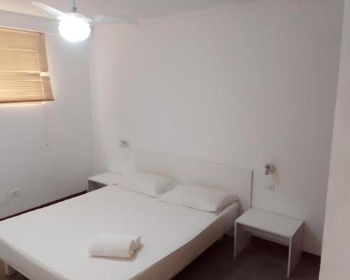 ein weißes Schlafzimmer mit einem Bett und einem Tisch in der Unterkunft Homeity Property in Mindelo