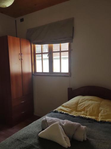 1 dormitorio con cama y ventana en Habitación en Cabaña del lago, en Coñaripe