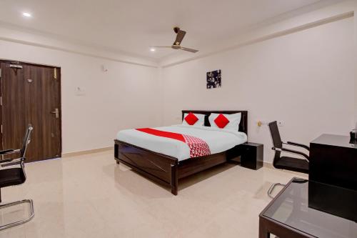 a bedroom with a bed and two chairs and a television at Super OYO Flagship 81926 Hotel MN Stays in Vijayawāda