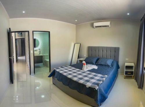 a bedroom with a blue bed and a bathroom at Fortu House in Carrillo