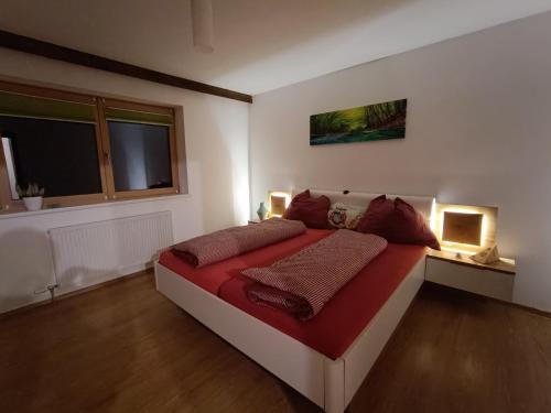 a bedroom with a large red bed with two lamps at Kathrins Ferienwohnung in Breitenbach am Inn