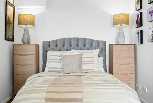 Un dormitorio con una cama con dos mesitas de noche y dos lámparas. en Romantic Ocean View Studio at Stanwell Tops, en Stanwell Park