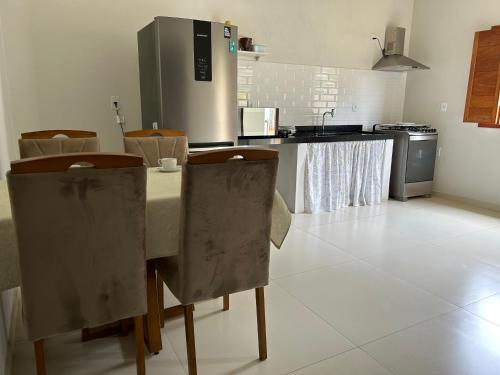 kuchnia ze stołem z krzesłami i lodówką w obiekcie Agradável Casa de Campo, recém construída. w mieście Divisa