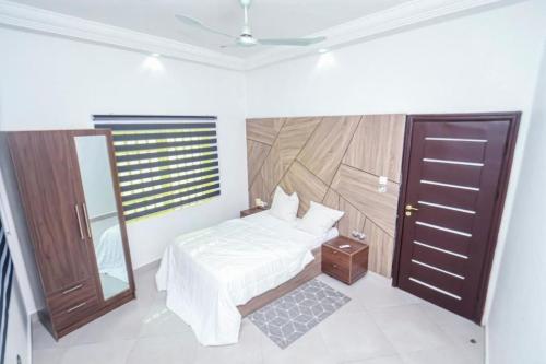 a bedroom with a bed and a mirror and a door at RESIDENCE MH SERVICES Cotonou in Cotonou
