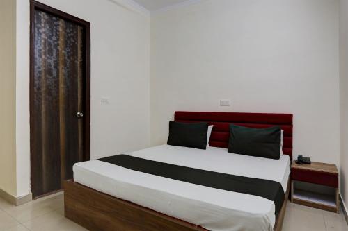 a bedroom with a large bed with a red headboard at Omi Inn Manesar in Manesar