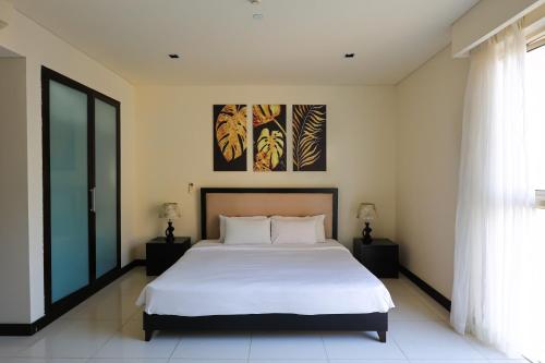 a bedroom with a white bed and a painting on the wall at The Sea Luxury Nha Trang Apartment in Nha Trang