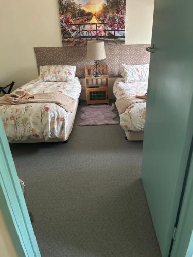 a bedroom with two beds and a table with a lamp at Butlers Guesthouse in Birregurra