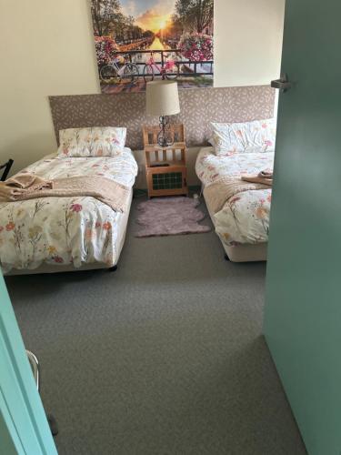 1 dormitorio con 2 camas y mesa con lámpara en Butlers Guesthouse, en Birregurra
