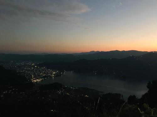 a view of a city and a lake at sunset at Hom's Homestay Retreat Sarangkot Pokhara in Pokhara